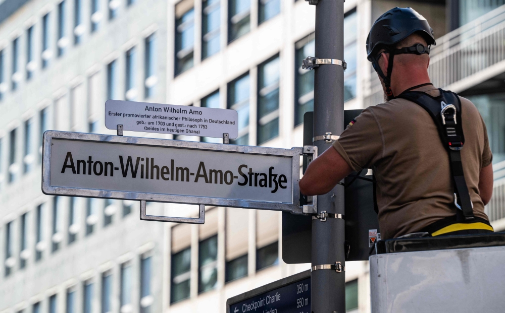 A worker installs a street sign bearing what is supposed to become the new name for the 'Mohrenstrasse' (Moor street), the 'Anton-Wilhelm-Amo-strasse' in Berlin on August 22, 2025. (Photo by John MacDougall / AFP)
