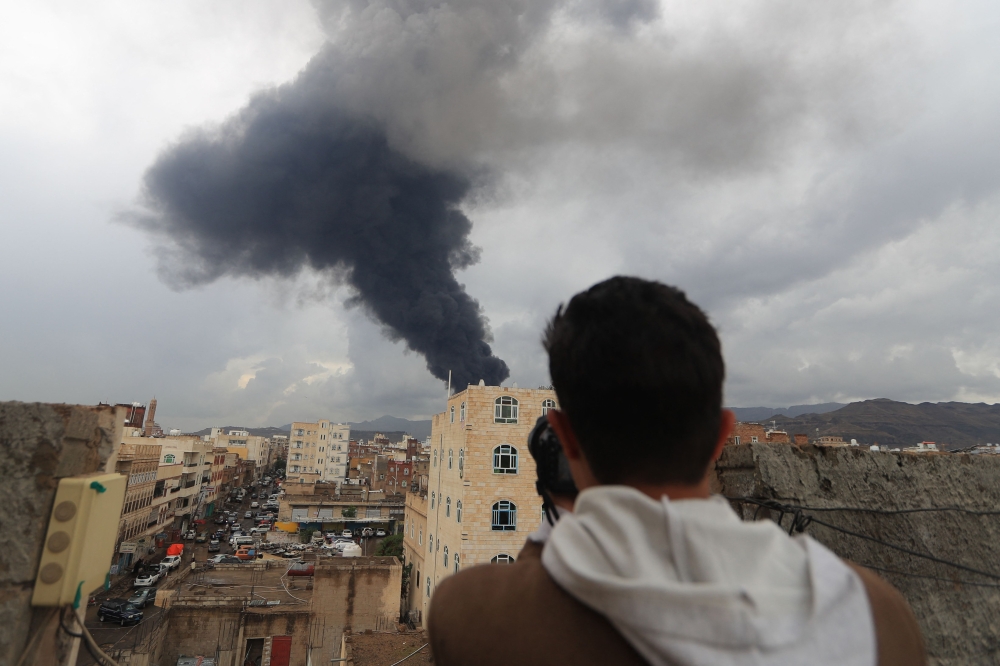 A photojournalist takes a picture of smoke after an Israeli air strike on Yemen's capital Sanaa on August 24, 2025. (Photo by Mohammed Huwais / AFP)