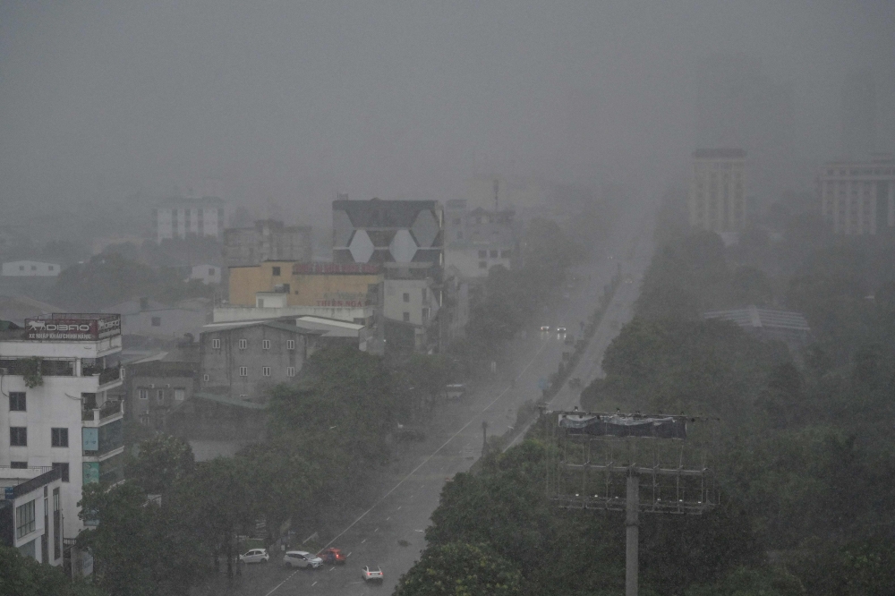 Rain falls above the buildings and a street in Vinh city, Nghe An province on August 25, 2025, before Typhoon Kajiki makes landfall in Vietnam. (Photo by Nhac Nguyen / AFP)