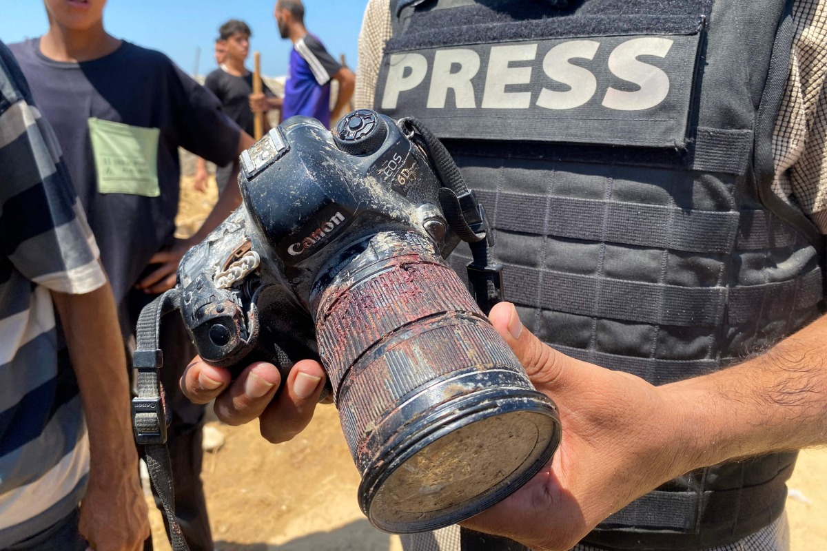 A journalist holds the blood-covered camera belonging to Palestinian photojournalist Mariam Dagga, a journalist who freelanced for AP since the start of the war and who was killed in an Israeli strike on Nasser hospital in Khan Yunis in the southern Gaza Strip, during her funeral on August 25, 2025. Photo by AFP
