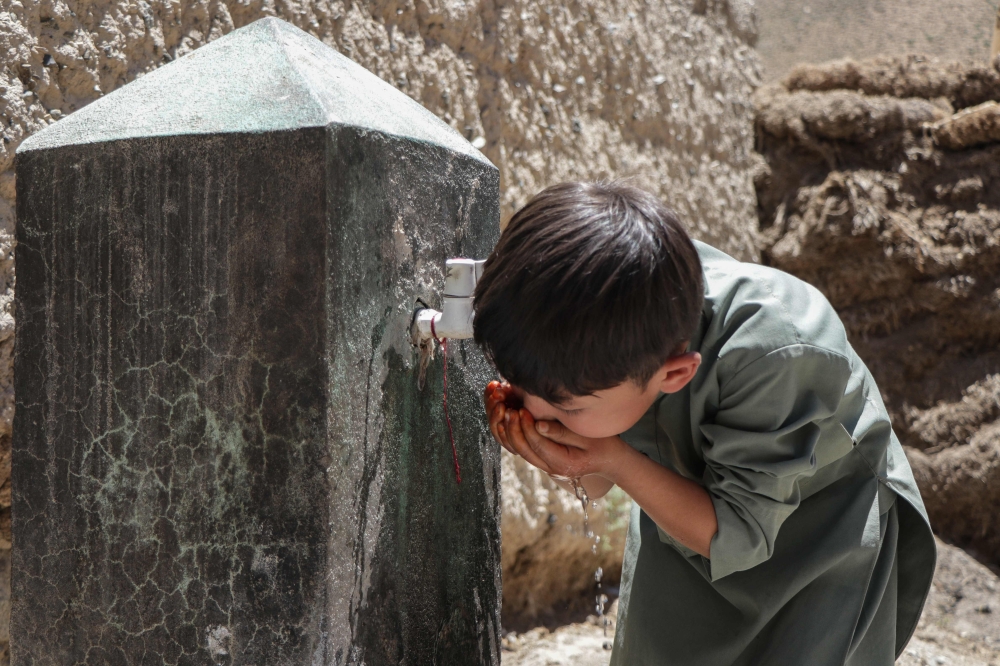 (Files) An Afghan Hazara boy drinks water from a tap in Qavariyak village in Shibar district of Bamiyan province on June 18, 2025. (Photo by Mohammad Faisal Naweed / AFP)