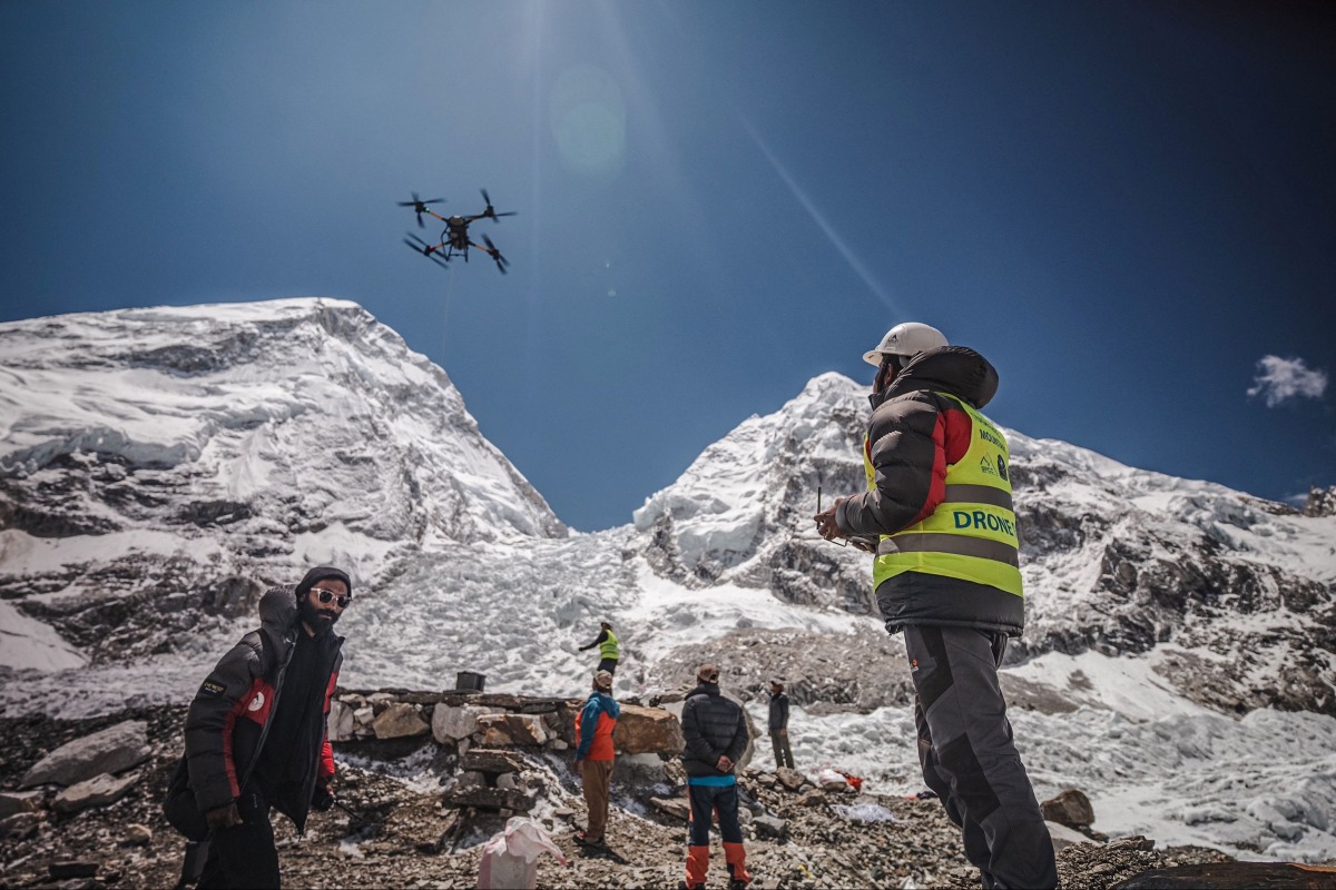 In this handout photograph taken on May 11, 2025 and released by Airlift Technology, a man operates a heavy-lift drone to clear trash dumped at the Everest Base Camp. Photo by Airlift Technology / AFP