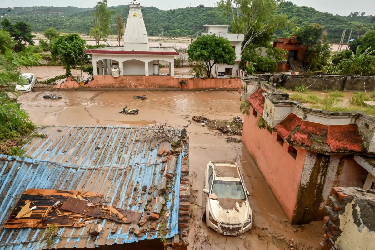 A damaged car is pictured under mud and debris after heavy rains induced flood in Jammu on August 27, 2025. Photo by AFP