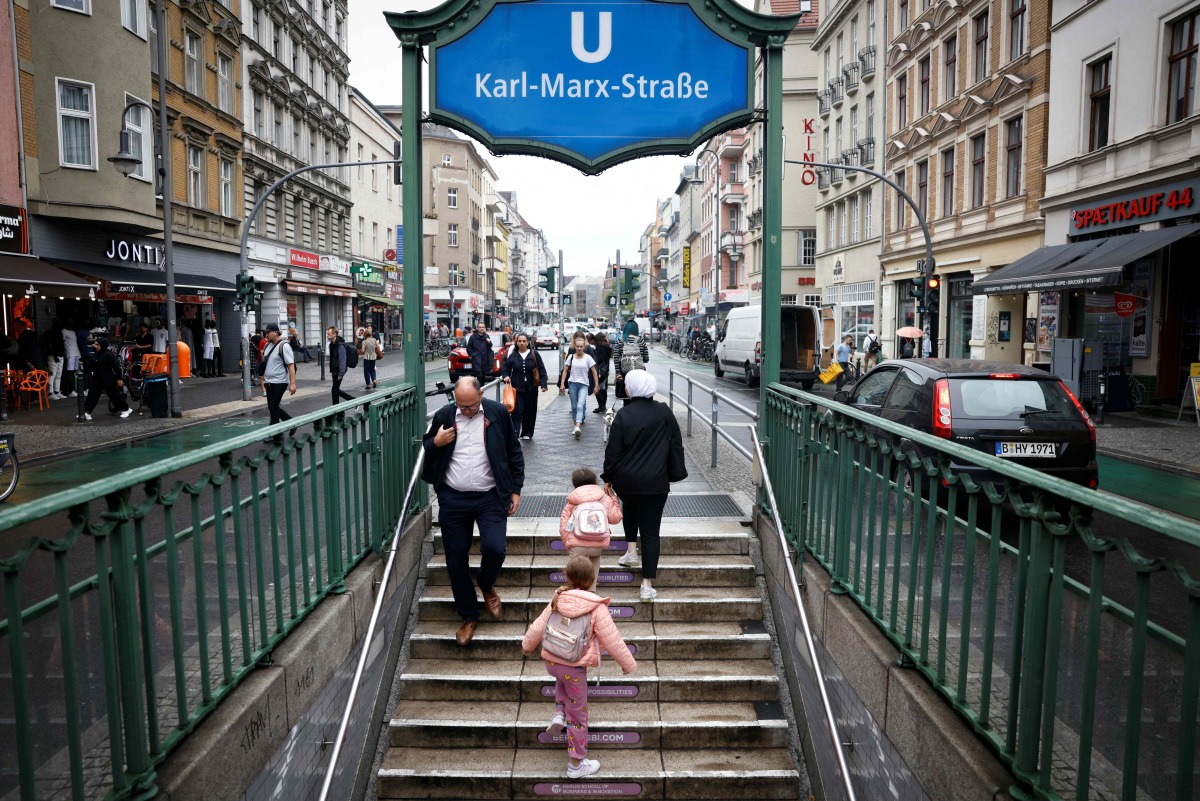 A family exits the metro station onto Karl Marx Strasse in the district of Neukoelln, Berlin on August 28, 2025. Photo by Odd ANDERSEN / AFP
