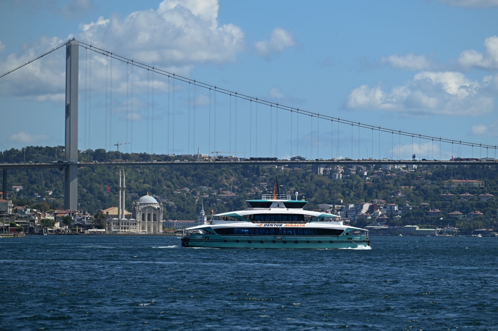 A new fast ferry sails on Bosphorus in Istanbul, on August 26, 2025, next to the 15 July Martyrs Bridge, known as Bosphorus bridge. (Photo by Ozan Kose / AFP)