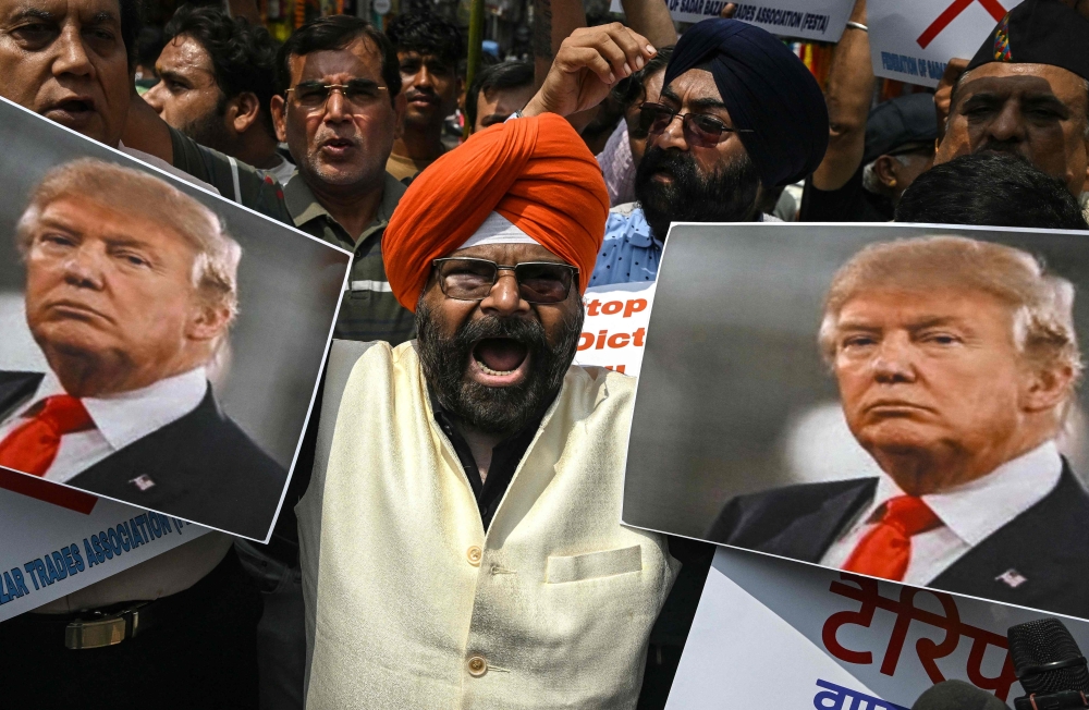 Members of a trades association holding a poster of US President Donald Trump shout slogans during a protest against the recent tariff hikes imposed by the US on India in New Delhi on August 30, 2025. (Photo by Arun SANKAR / AFP)
