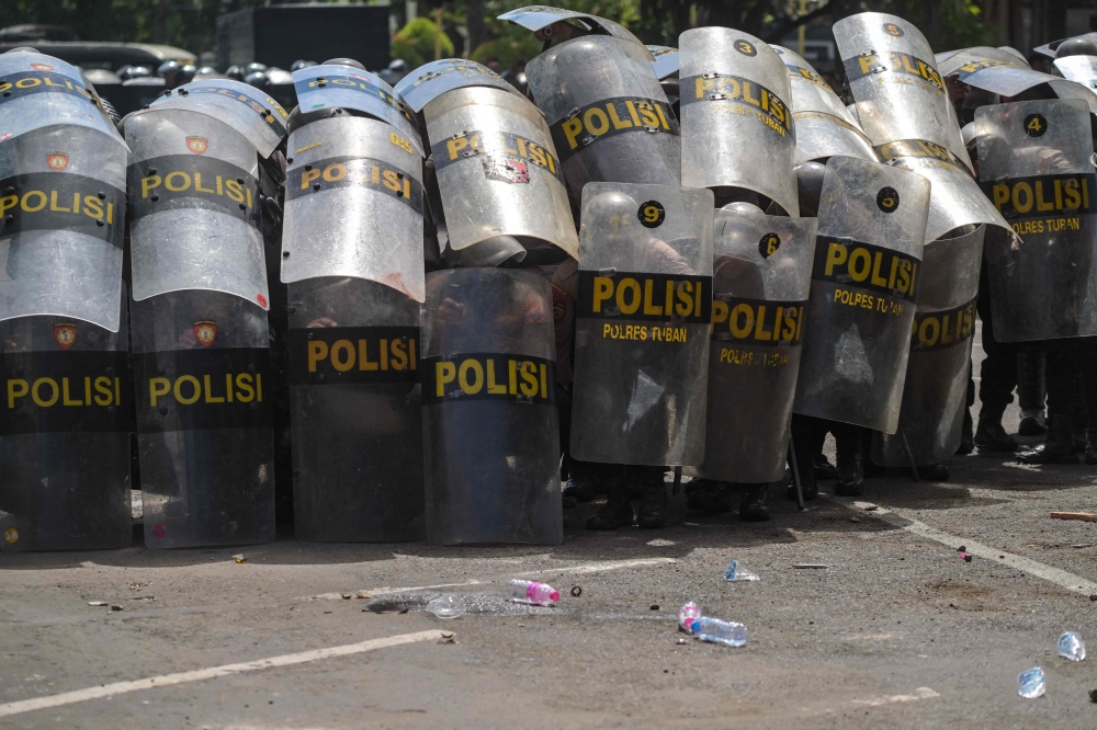 Police raise their shields during a protest in front of the Regional Police headquarters in Surabaya on August 30, 2025. (Photo by Juni Kriswanto / AFP)