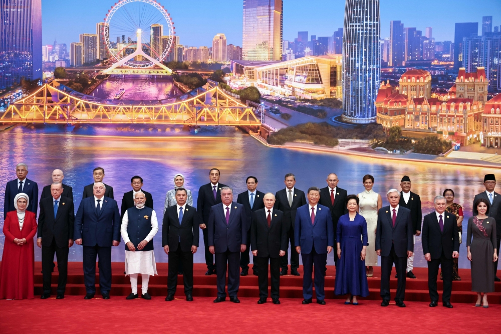In this pool photograph distributed by the Russian state agency Sputnik, Russia's President Vladimir Putin, Chinese President Xi Jinping, his wife Peng Liyuan and foreign leaders pose during a family photo of the Shanghai Cooperation Organization (SCO) Summit in Tianjin on August 31, 2025. (Photo by Alexander Kazakov / POOL / AFP)