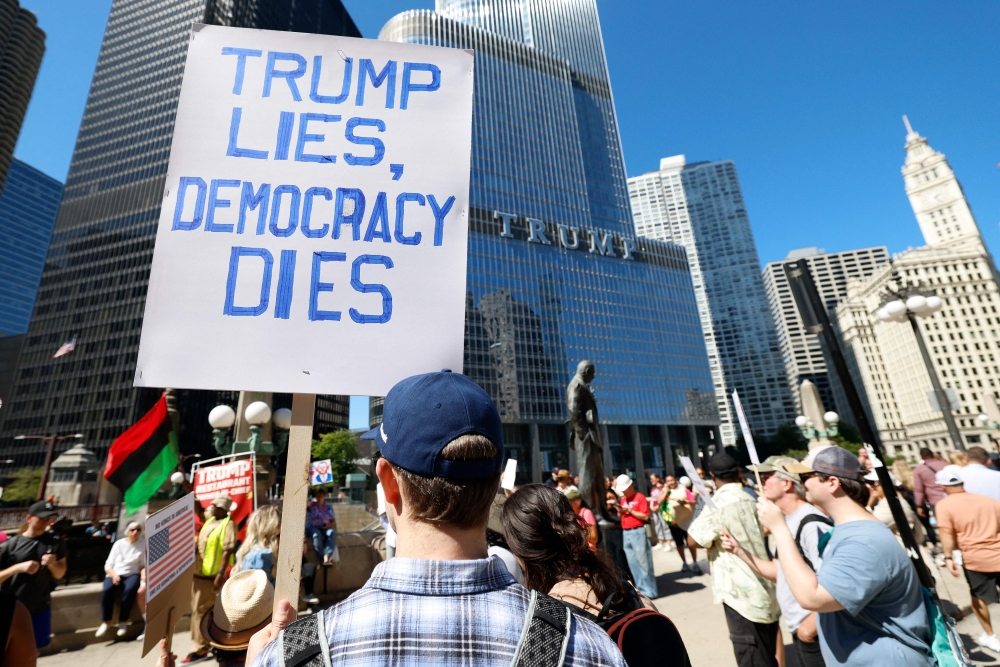Protesters hold signs reading 