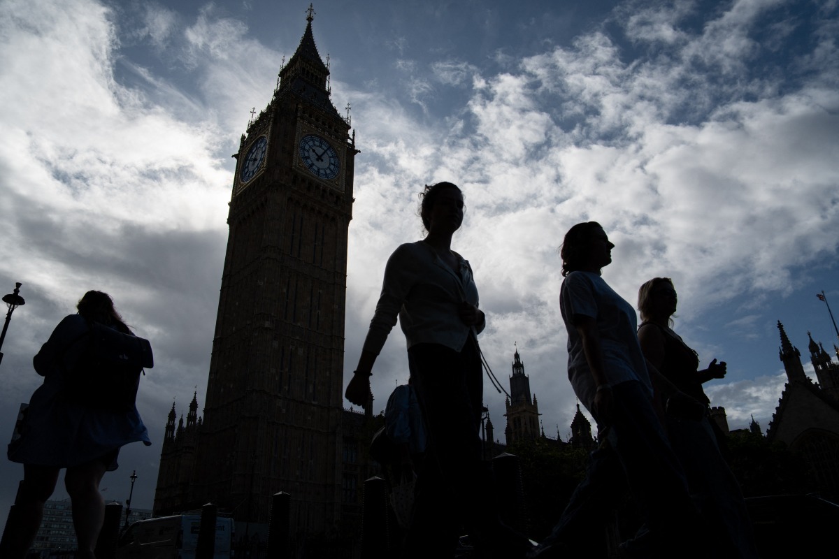 Pedestrians walk past the Elizabeth Tower, commonly known by the name of the clock's bell 