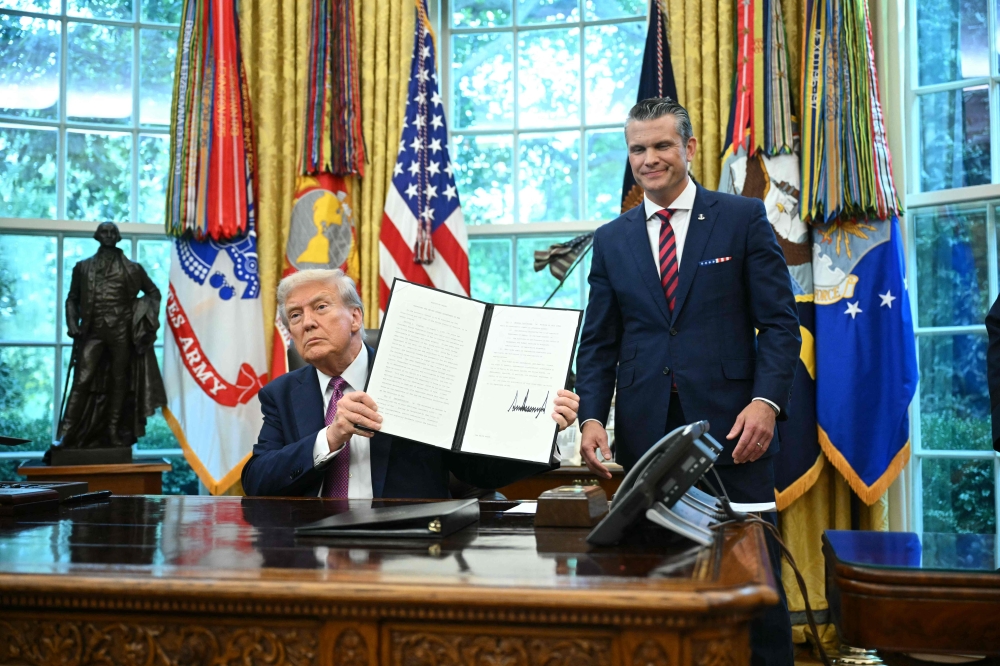 US President Donald Trump shows a signed executive order next to the Secretary of Defense Pete Hegseth in the Oval Office of the White House in Washington, DC on September 5, 2025. (Photo by Mandel Ngan / AFP)