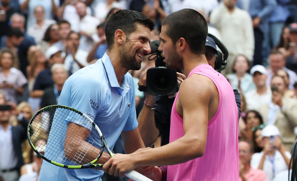Spain's Carlos Alcaraz and Serbia's Novak Djokovic (L) hug at the net after Alcaraz's victory on September 5, 2025. (Photo by Timothy A. Clary / AFP)
 