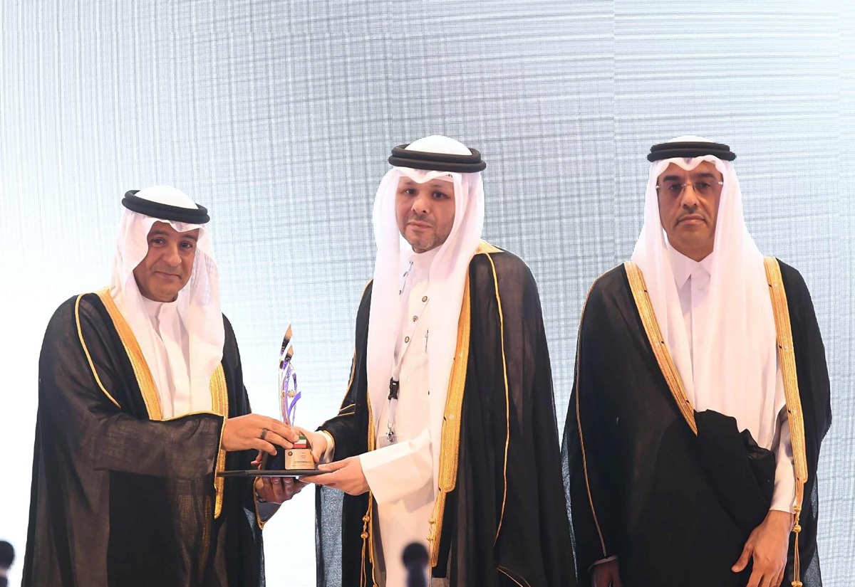 Minister of Labour, H E Dr Ali bin Samikh Al Marri, looks on as QNB official receives an award for supporting national employment during the event.