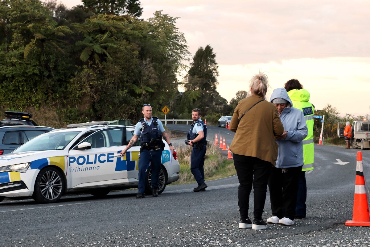 Police officers and locals stand near a roadblock where a police shootout occurred near the town of Piopio, located in New Zealand痴 Waikato region on September 8, 2025. Photo by DJ MILLS / AFP