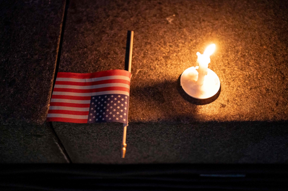 A US flag and a candle sit on a step during a candlelight vigil and prayer event for Turning Point USA Founder Charlie Kirk on September 10, 2025 in Seattle, Washington. David Ryder/Getty Images/AFP 