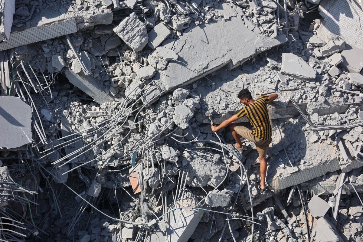 A Palestinian youth climbs the rubble of al-Ghafari tower after its destruction by Israeli airstrikes in Gaza City on September 15, 2025. Photo by Omar AL-QATTAA / AFP