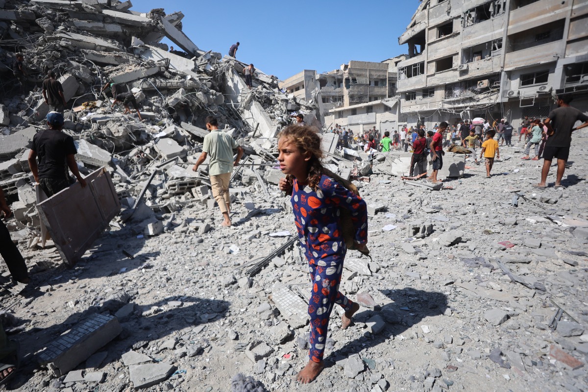 Displaced Palestinians salvage items from the rubble of the al-Ghafari tower after it was destroyed in Israeli strikes in Gaza City on September 15, 2025. Photo by Omar AL-QATTAA / AFP