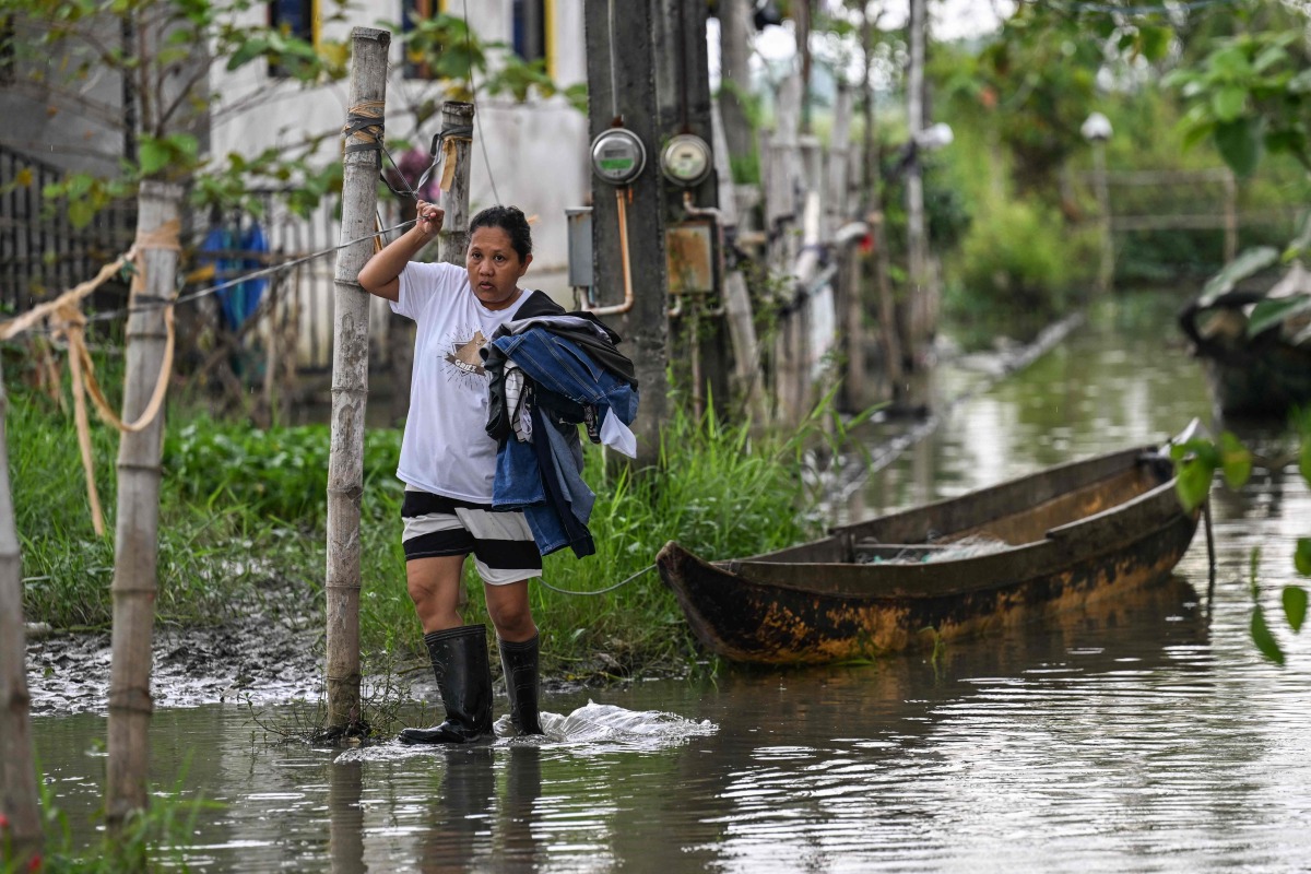 In this photo taken on September 15, 2025, a resident wades through a flooded area in Calumpit, Bulacan. Photo by Jam STA ROSA / AFP