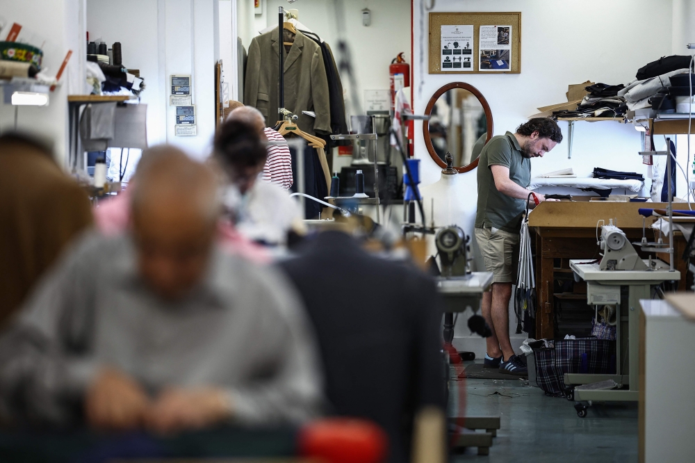 Apprentice tailor Charlie makes adjustments to a jacket at Henry Poole & Co on Savile Row in London on August 12, 2025. (Photo by Henry Nicholls / AFP)