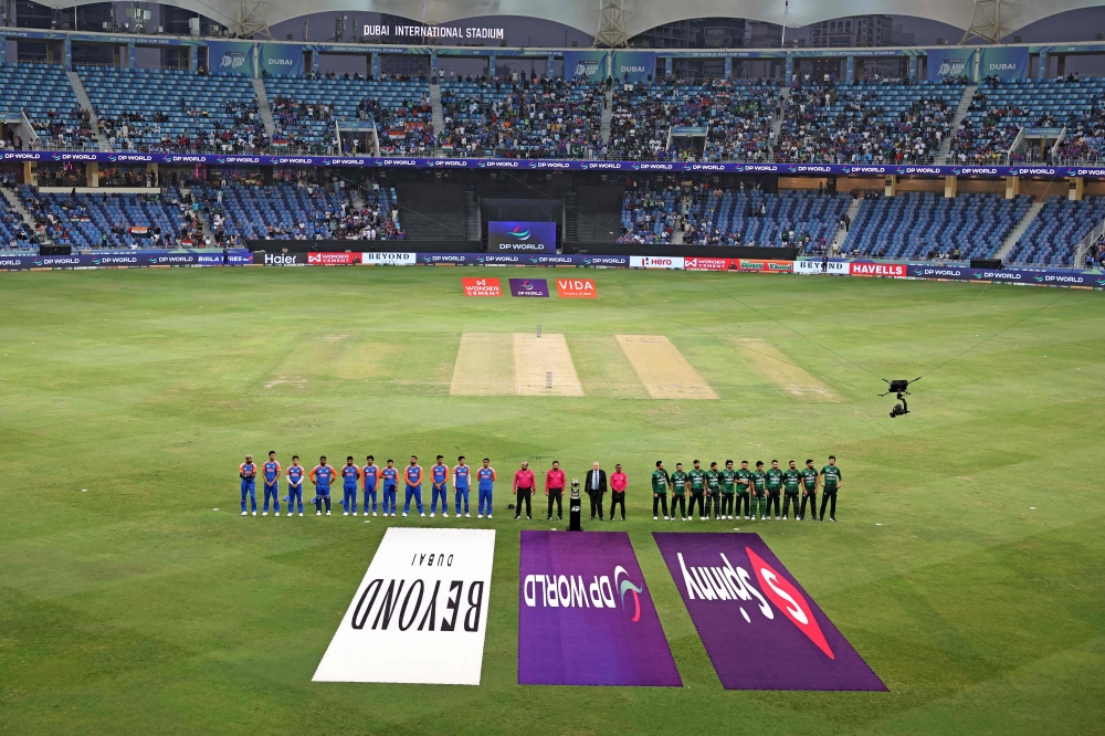 Indian and Pakistani players stand for their national anthem at the start of the Asia Cup 2025 Super Four Twenty20 international cricket match between India and Pakistan at the Dubai International Stadium in Dubai on September 21, 2025. (Photo by Fadel SENNA / AFP)