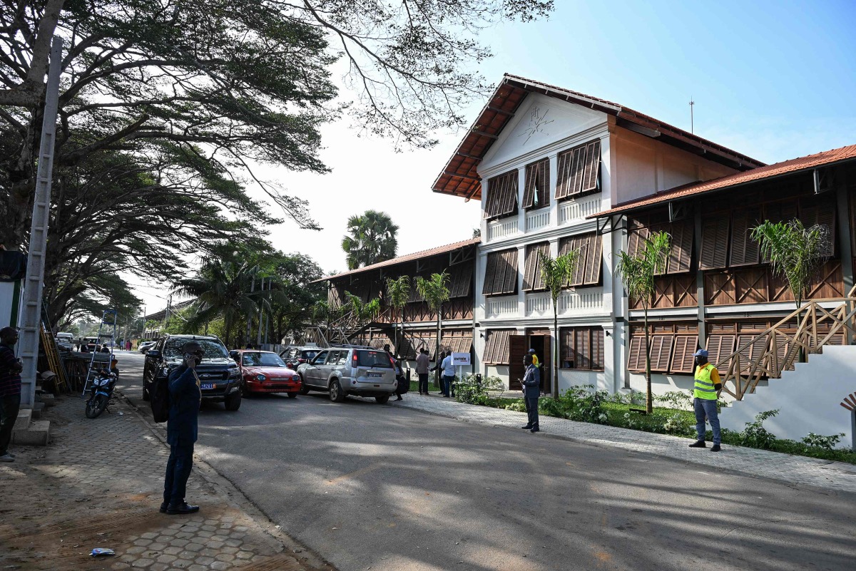 A view of people standing in front of the contemporary arts museum called the House of Art, a former post office and customs building, a remnant of the colonial era, of the Societe General Cote d'Ivoire (SGBCI) foundation in Grand-Bassam, a city listed as a UNESCO World Heritage Site, on September 25, 2025. (Photo by Sia KAMBOU / AFP)