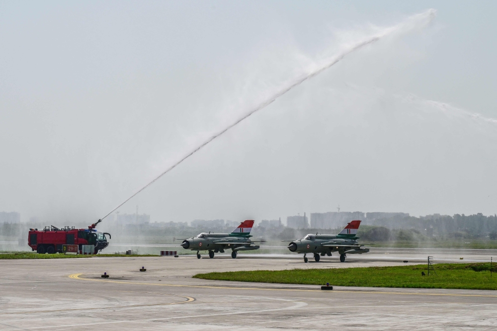 A firefighter gives a water cannon salute to India's MiG-21 fighter jets during their farewell ceremony at the Chandigarh Air Force Station in Chandigarh on September 26, 2025. (Photo by AFP)
