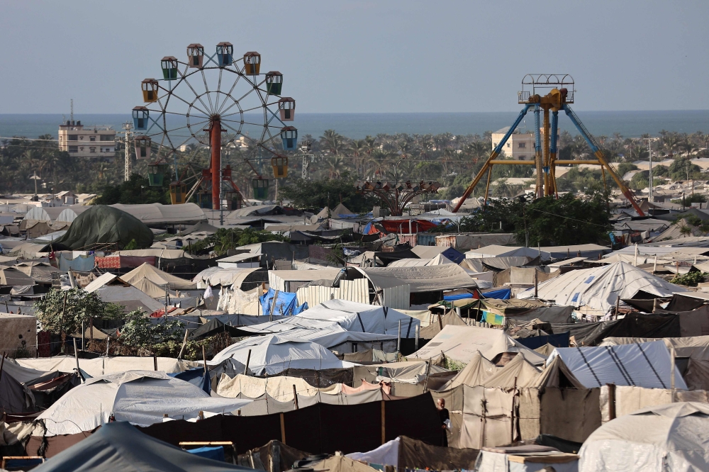 An idle ferris wheel stands near tents at a camp for displaced people in Khan Yunis in the southern Gaza Strip, on September 29, 2025. (Photo by Omar Al-Qattaa / AFP)