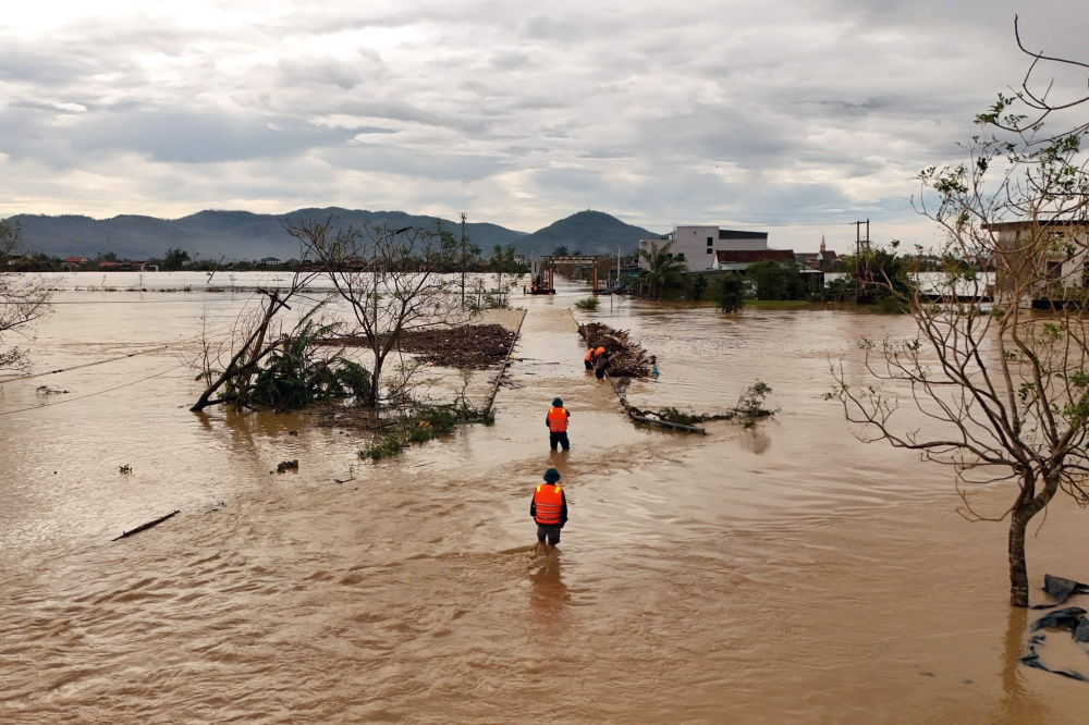 An aerial photo shows rescue workers walking through flood waters after typhoon Bualoi passed over Lam Thanh commune in Nghe An province on September 30, 2025. (Photo by Phan Duy / AFP)