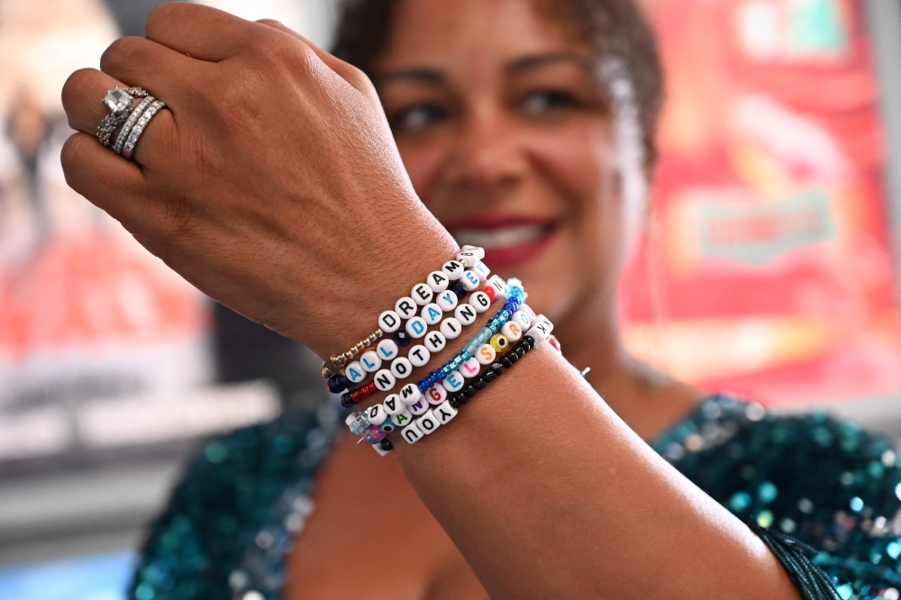 A fan shows her bracelet spelling out song titles written by Taylor Swift as they attend 