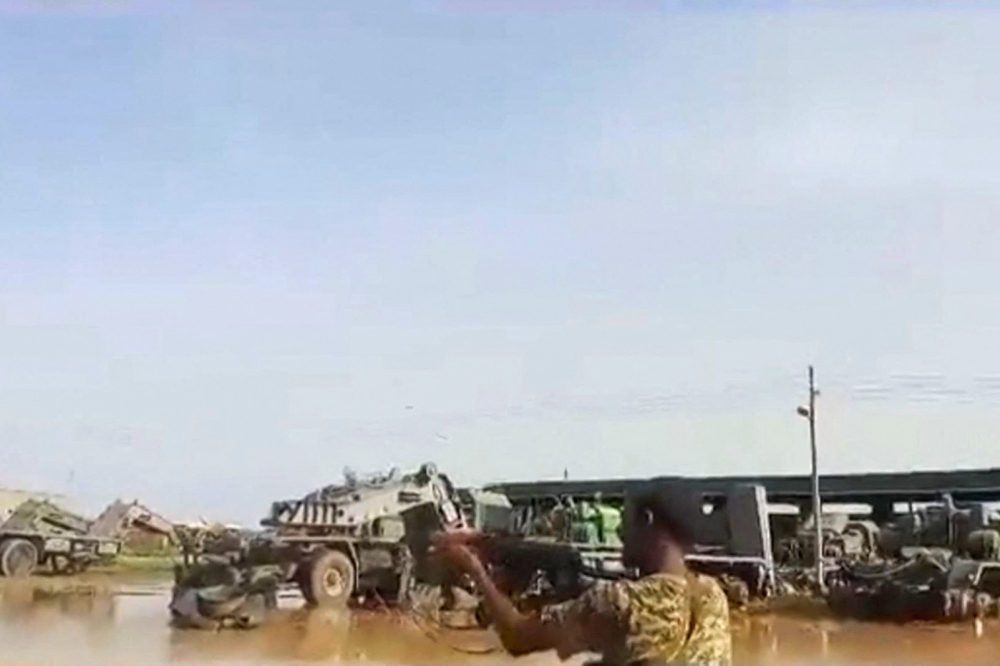 A grab from a UGC video posted on the X platform on August 22, 2023 reportedly shows members of the Sudanese army firing at Rapid Support Forces (RSF) fighters in what they say is the al-Shajara military base in Khartoum. (Photo by UGC / AFP)