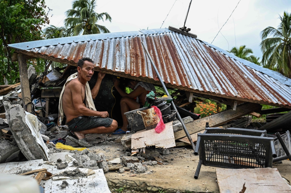 Men look for items in a collapsed house in Manay, in the province of Davao Oriental on October 11, 2025. (Photo by Jam Sta Rosa / AFP)

