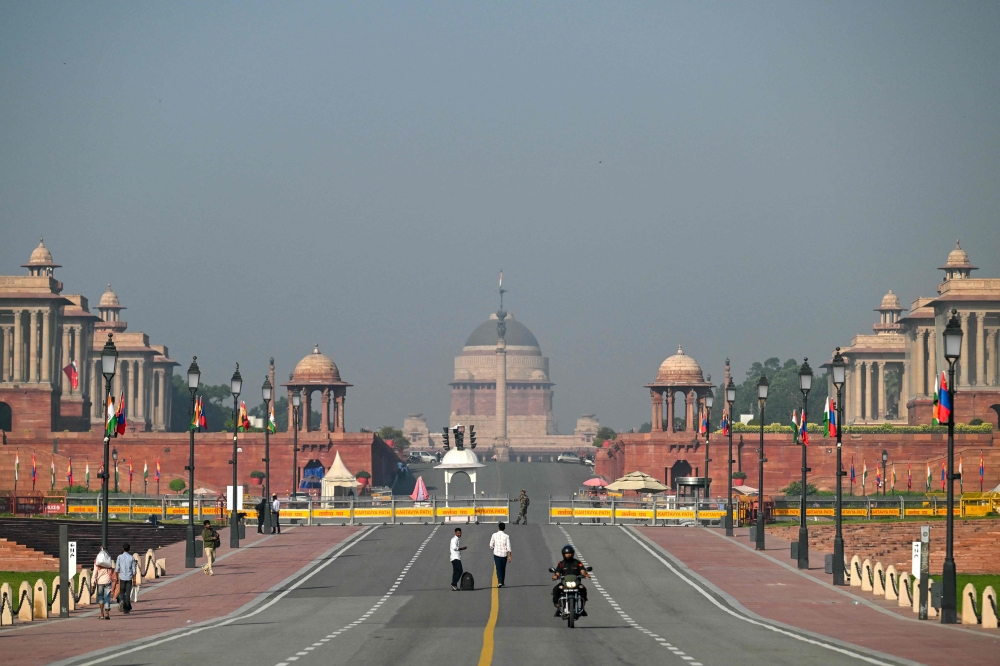 People walk past Kartavya Path near India's presidential palace (Rashtrapati Bhavan) in New Delhi on October 14, 2025. (Photo by Arun Sankar / AFP)