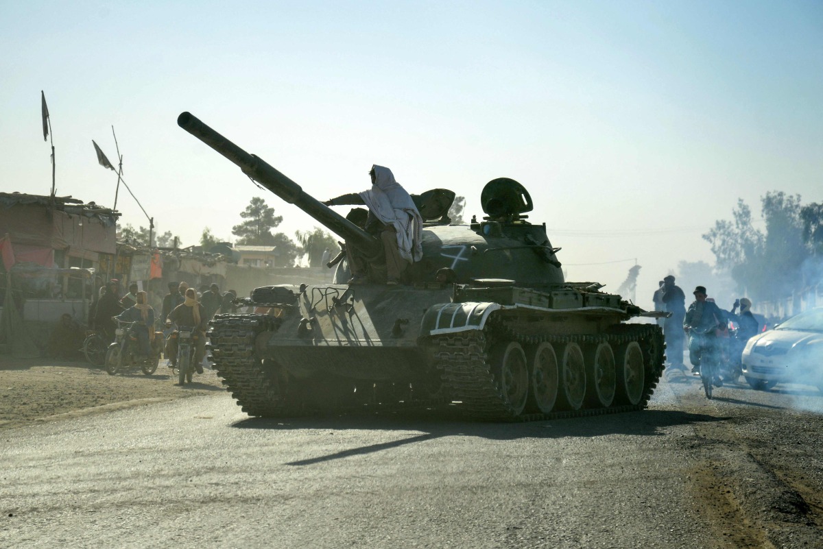 Taliban security personnel on a Soviet-era tank are followed by motorcyclists as they ride towards the border, as clashes take place between Taliban security personnel and Pakistani border forces, in the Spin Boldak district of Kandahar Province on October 15, 2025. (Photo by Sanaullah SEIAM / AFP)
