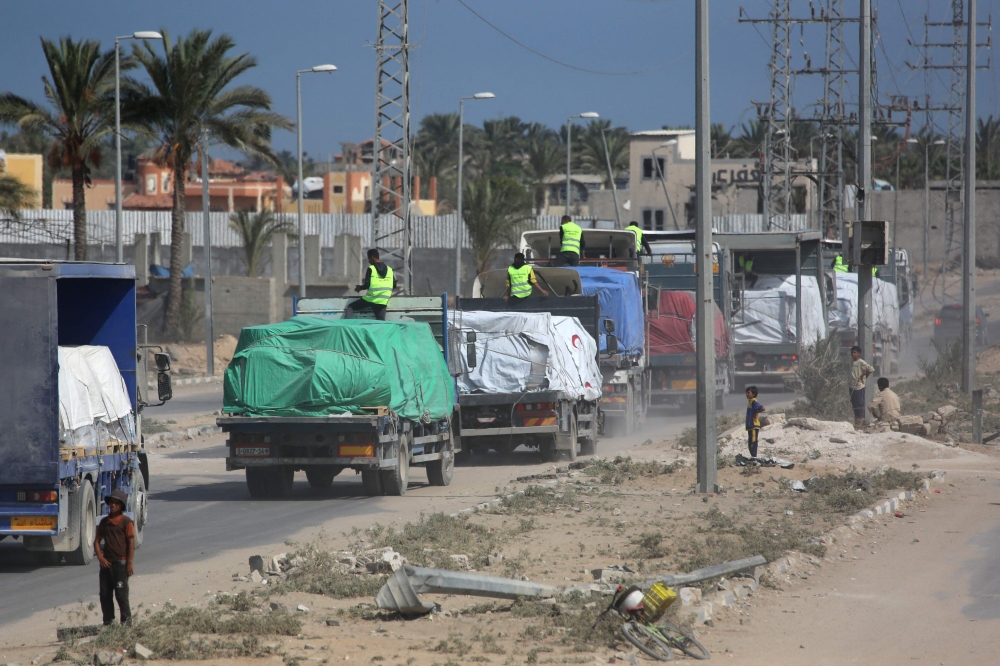Trucks carrying aid provided by the World Food Programme (WFP) drive on a road in Deir el-Balah on October 17, 2025. (Photo by Bashar Taleb / AFP)