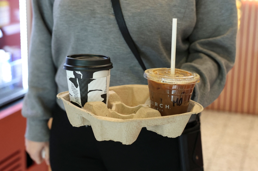 A customer holds a tray with coffee drinks in New York City on October 16, 2025. (Photo by Angela Weiss / AFP)
