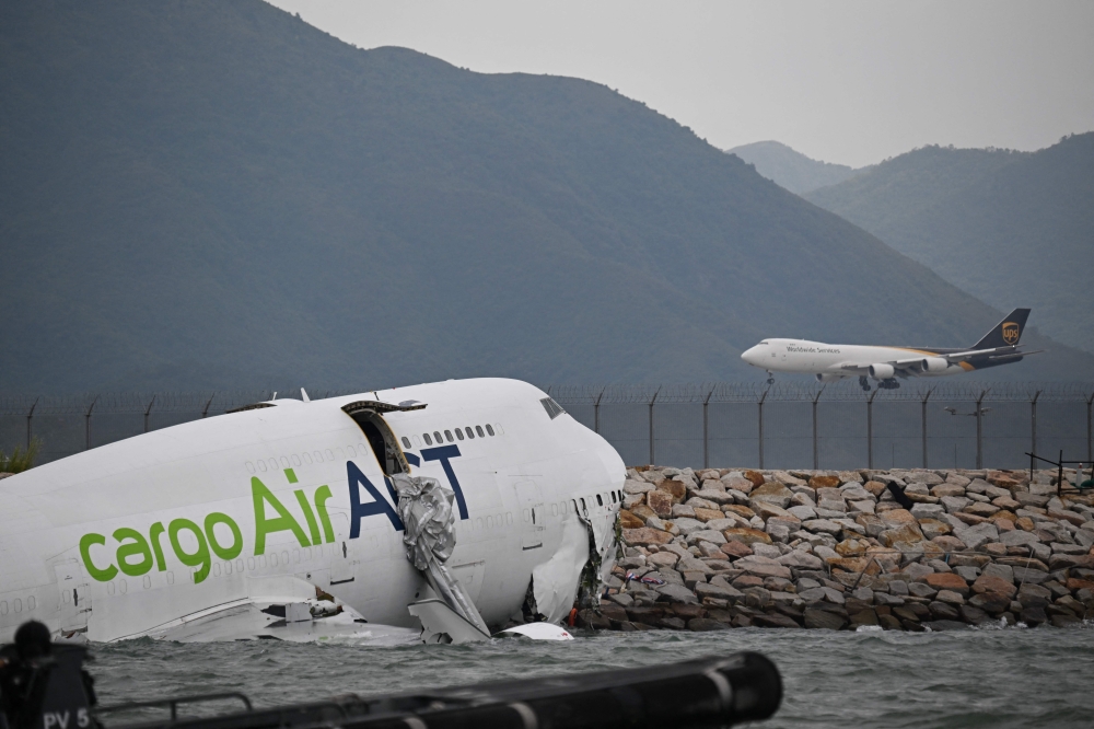 An ACT Airlines Boeing 747-400 cargo aircraft (L), wet leased by Emirates SkyCargo, is seen in the water after veering off the runway on October 20, 2025. (Photo by Peter Parks / AFP)
 