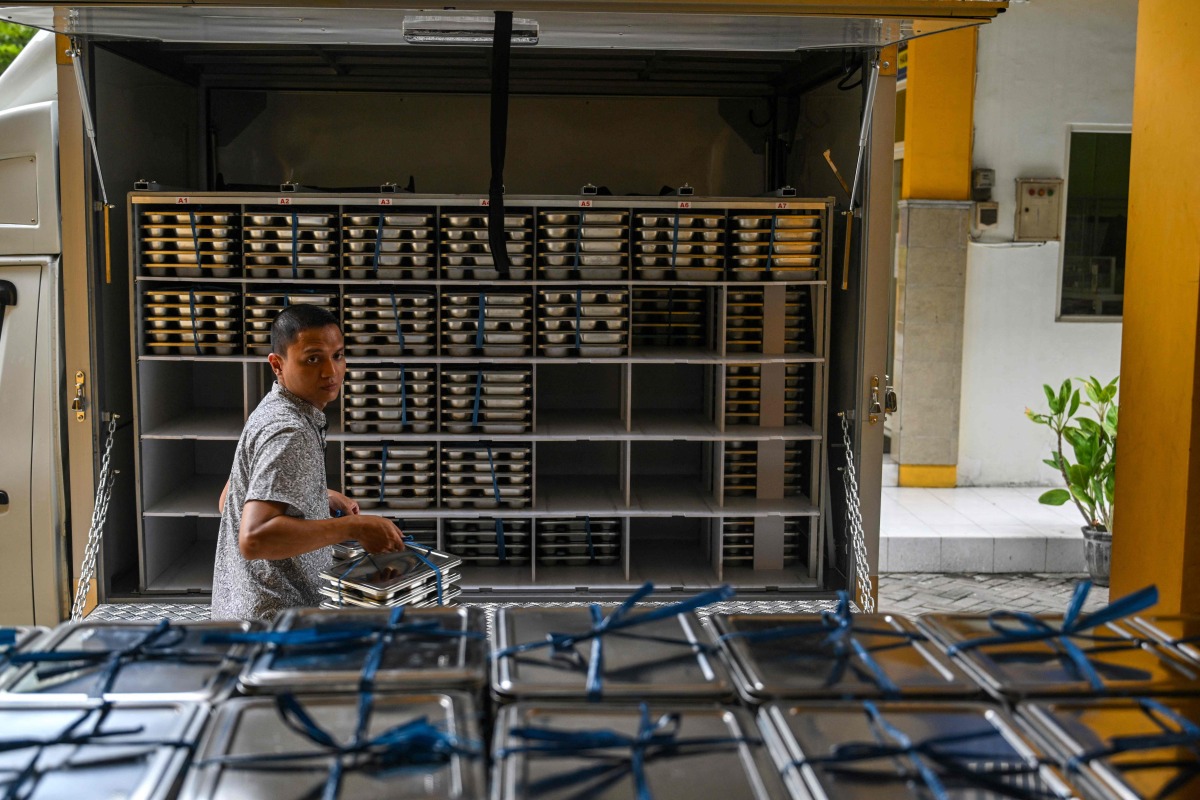 A staff member loads lunch plates on the first day of a free-meal programme at Muhammadiyah high school in Sidoarjo on January 6, 2025. Photo by Juni KRISWANTO / AFP