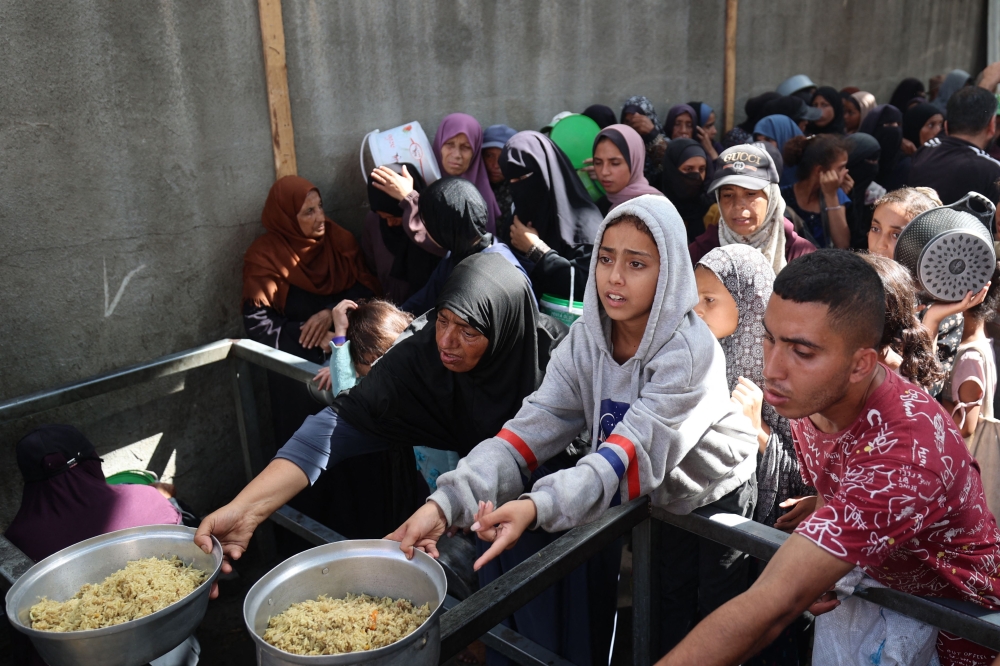 Palestinian children gather to receive food portions from a charity kitchen in the Nuseirat refugee camp, located in the central Gaza Strip, on October 21, 2025. (Photo by Eyad Baba / AFP)