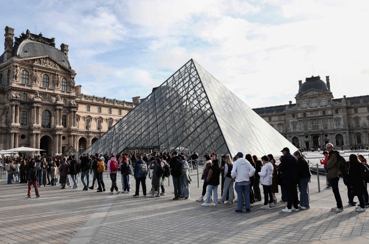 Visitors queue in front of the Pyramide du Louvre, designed by Chinese-US architect Ieoh Ming Pei, with the Louvre Museum in the background in Paris on October 22, 2025. (Photo by Thibaud MORITZ / AFP)