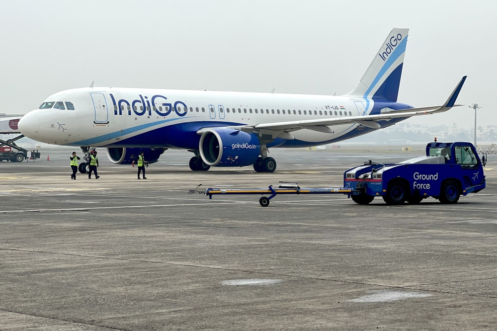 (Files) Ground staff walk past an Indigo airlines aircraft taxiing in the apron at the Netaji Subhash Chandra Bose International airport in Kolkata on February 1, 2024. (Photo by Indranil Mukherjee / AFP)