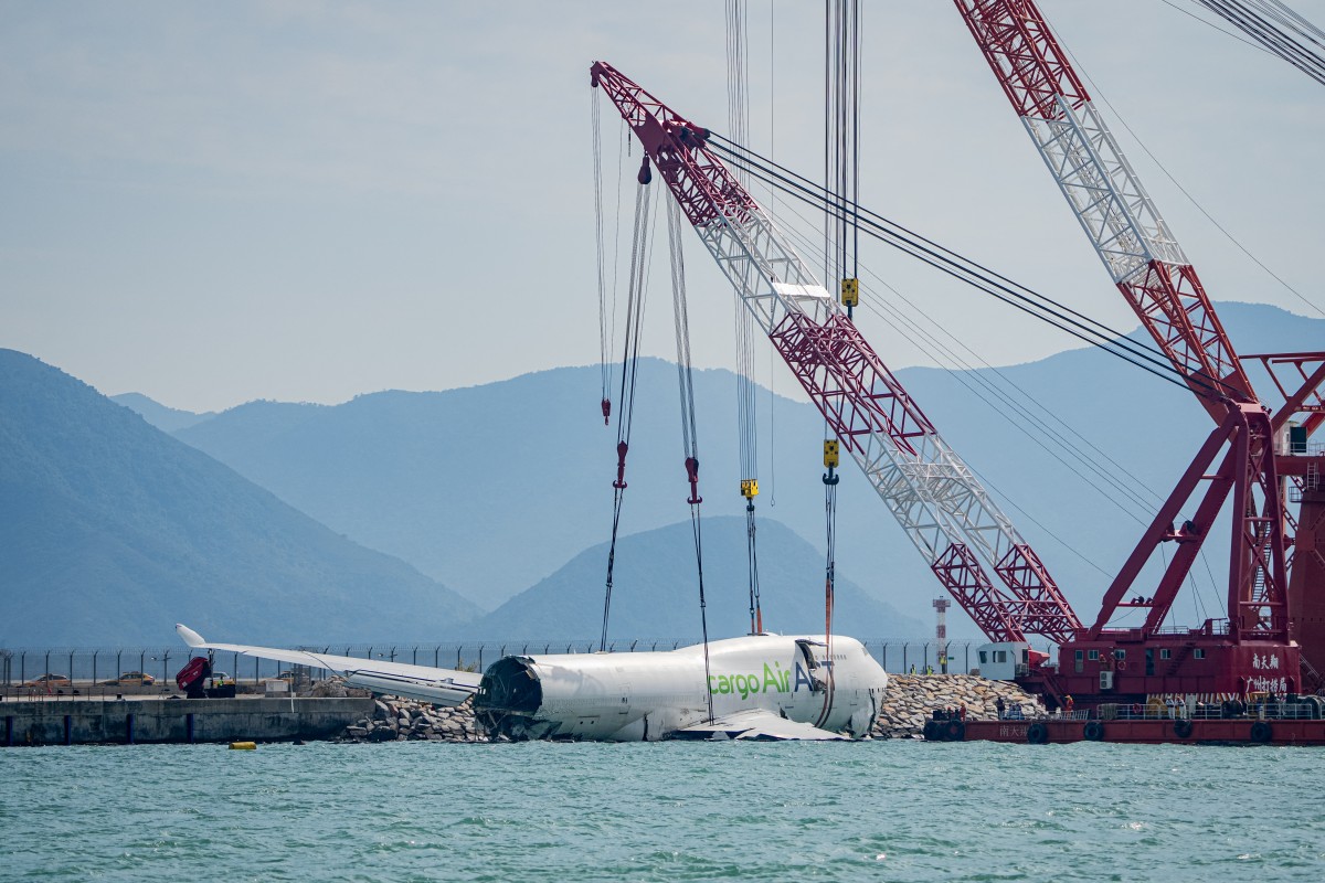 A crane hoists the recovered fuselage section of an ACT Airlines Boeing 747-400 cargo aircraft, in Hong Kong on October 26, 2025, after it veered off an airport runway on October 20 during landing. (Photo by Leung Man Hei / AFP)