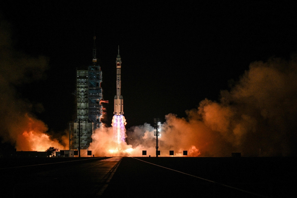 A Long March-2F carrier rocket, carrying the Shenzhou-21 spacecraft and a crew of three astronauts, lifts off from the Jiuquan Satellite Launch Centre in the Gobi desert, in northwest China on October 31, 2025. (Photo by Hector Retamal / AFP)