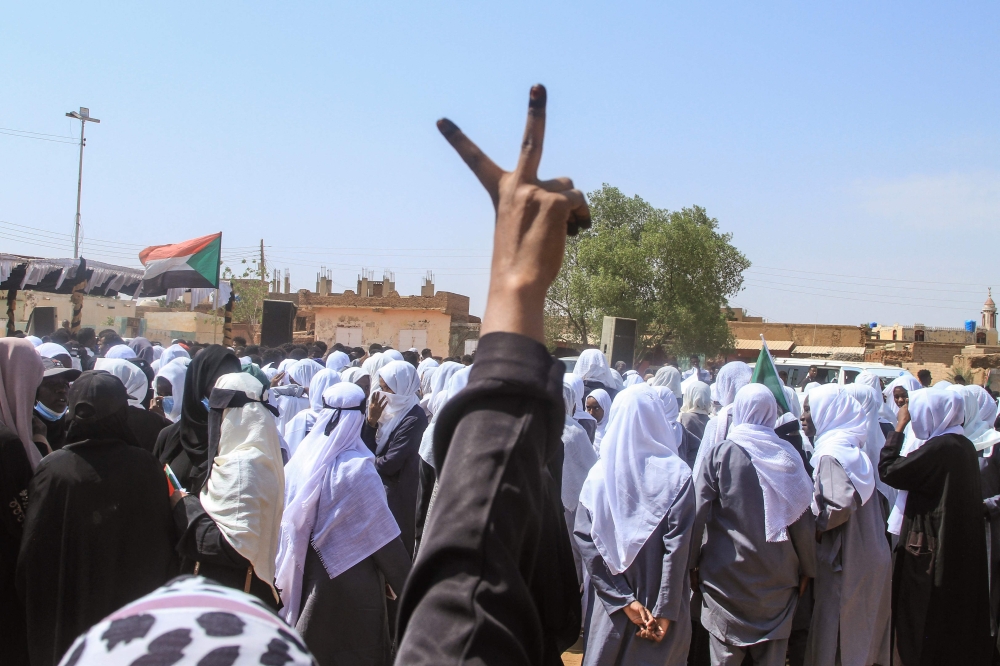 A Sudanese Student flashes the V-sign for victory as schools in the East Nile region of the capital gather during a protest against violations committed by the Rapid Support Forces (RSF) against the people of El- Fasher, in Khartoum on November 3, 2025. (Photo by Ebrahim Hamid / AFP)
