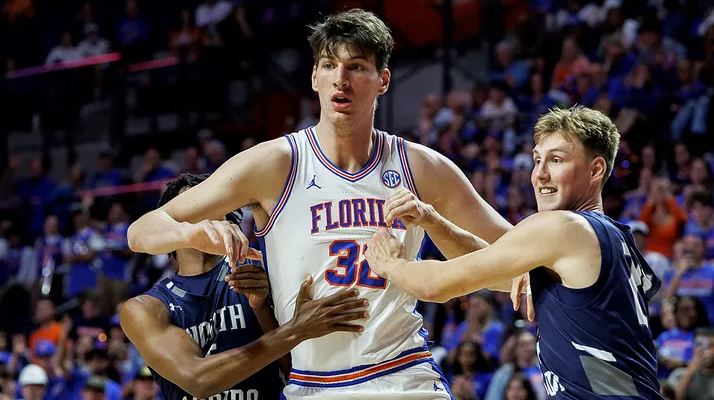 North Florida guard Dante Oliver, left, and North Florida forward Nestor Dyachok, right, guard against Florida center Olivier Rioux, center, in Gainesville, Florida. Chris Watkins/AP Photo