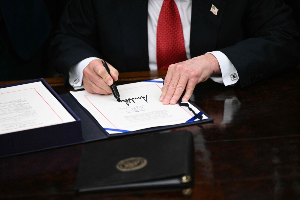US President Donald Trump signs the bill package to re-open the federal government in the Oval Office of the White House in Washington, DC, on November 12, 2025. (Photo by Brendan Smialowski / AFP)