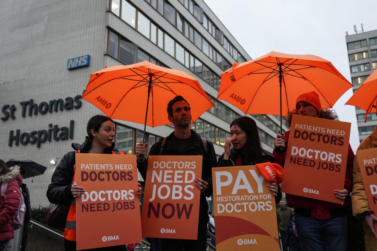 Staff members hold placards as they stand on a picket line on the first day of a five-day resident doctors' strike outside St Thomas' Hospital in central London on November 14, 2025. (Photo by CARLOS JASSO / AFP)
