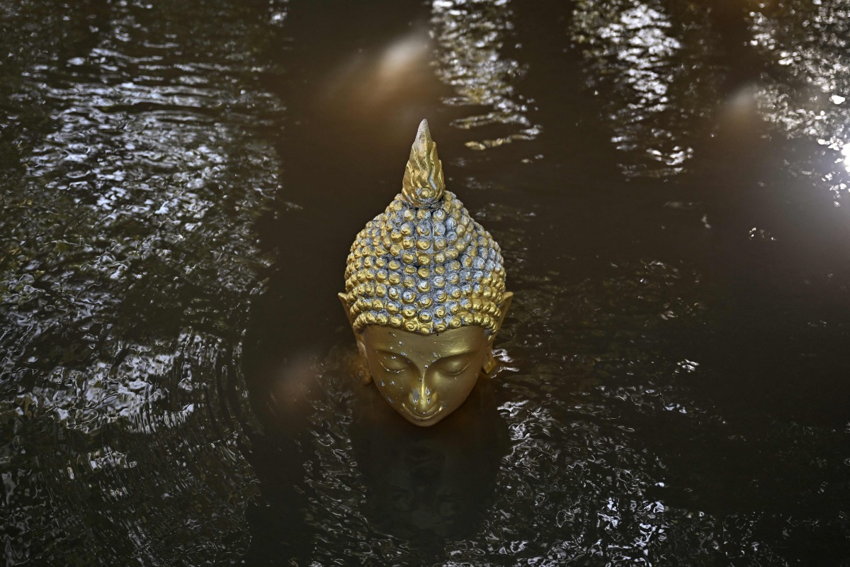 Floodwaters cover a Buddhastatue of at Wat Taku Buddhist temple in Bang Ban district in the central Thai province of Ayutthaya on November 14, 2025. (Photo by Lillian SUWANRUMPHA / AFP)
