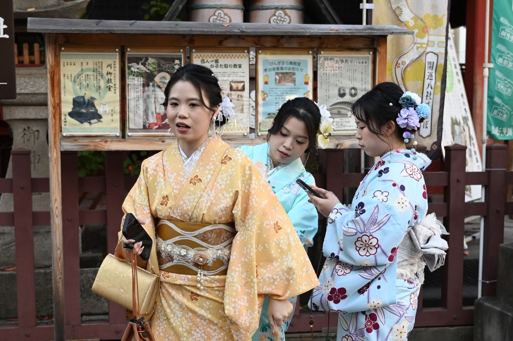 Chinese tourists adjust their kimono as they visit the Sensoji Temple in the Asakusa district of Tokyo on November 15, 2025. (Photo by Greg Baker / AFP)