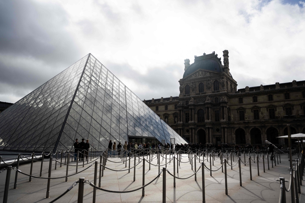 Tourists queue to enter the Louvre museum next to the Louvre pyramid designed by Chinese-US architect Ieoh Ming Pei, in Paris, on November 3, 2025. A gallery in the Louvre was closed to the public due to the building's 