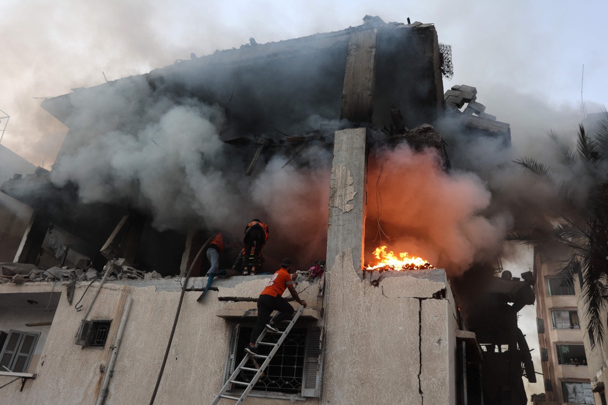 Civil defence personnel search a burning house targeted by Israeli airstrikes in Gaza City, on November 22, 2025. (Photo by Omar AL-QATTAA / AFP)